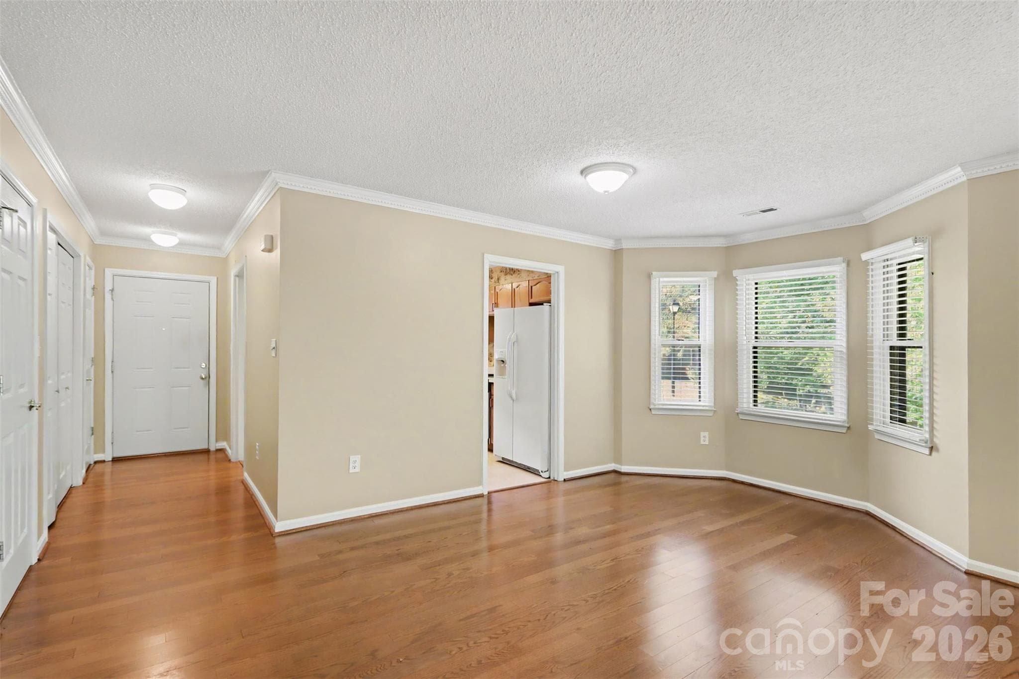 View from the dining area into the living room, featuring wood-look flooring, a brick gas fireplace, and glass doors opening to the rear patio. - 8407 Coulwood Oak Lane, Charlotte