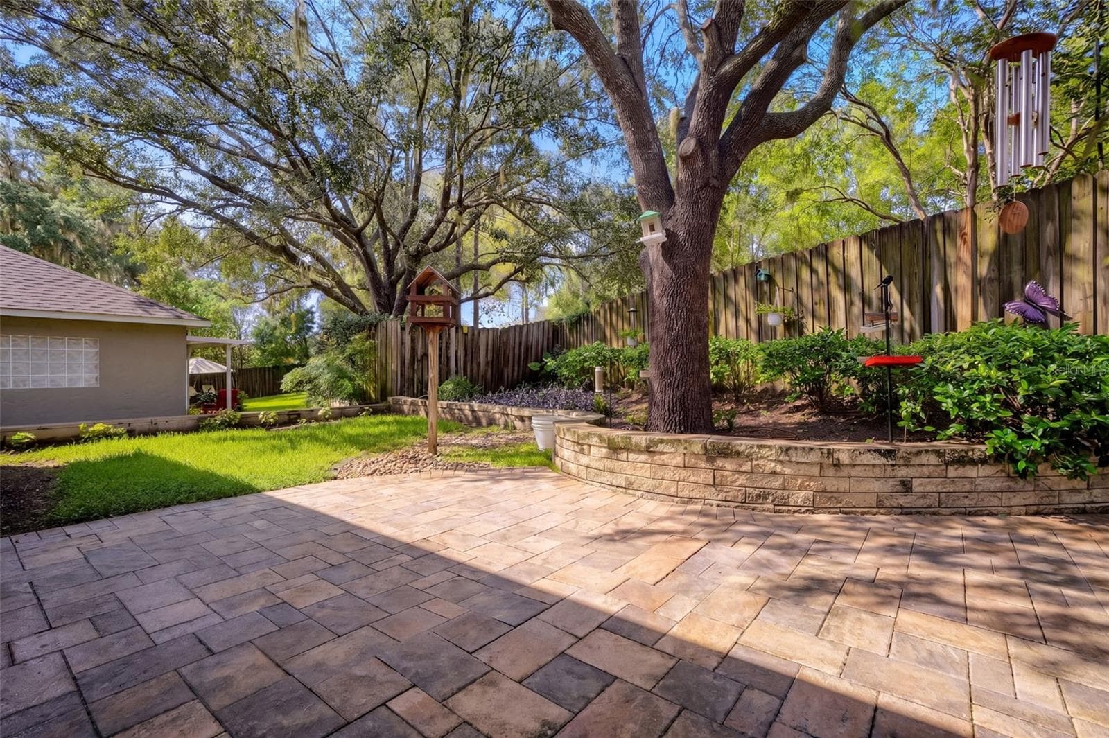 Brick pavers, mature landscaping, and the shade of a large oak create an inviting backyard retreat. - 71 ORANGE BLOSSOM DR, EUSTIS