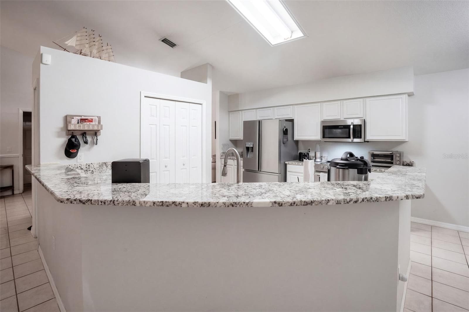 Granite countertops and a generous breakfast bar provide everyday workspace and casual seating. - 71 ORANGE BLOSSOM DR, EUSTIS