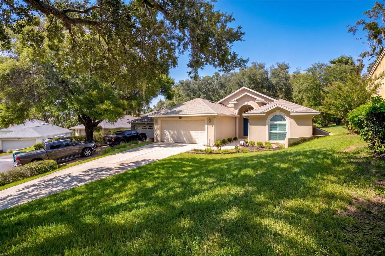 The front elevation is framed by mature landscaping and a broad shade tree. - 71 ORANGE BLOSSOM DR, EUSTIS