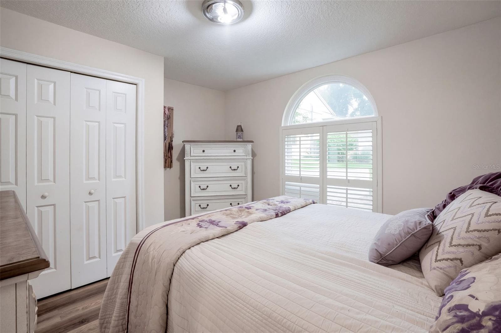An arched window brings natural light into the primary bedroom. - 71 ORANGE BLOSSOM DR, EUSTIS