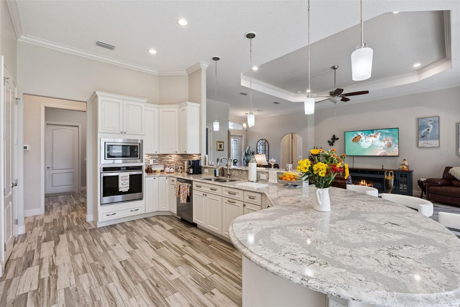 Enjoy family gatherings in the spacious kitchen, featuring a beautiful curved quartz island with comfortable seating for 8 or more. - 36819 WOLF CT, EUSTIS