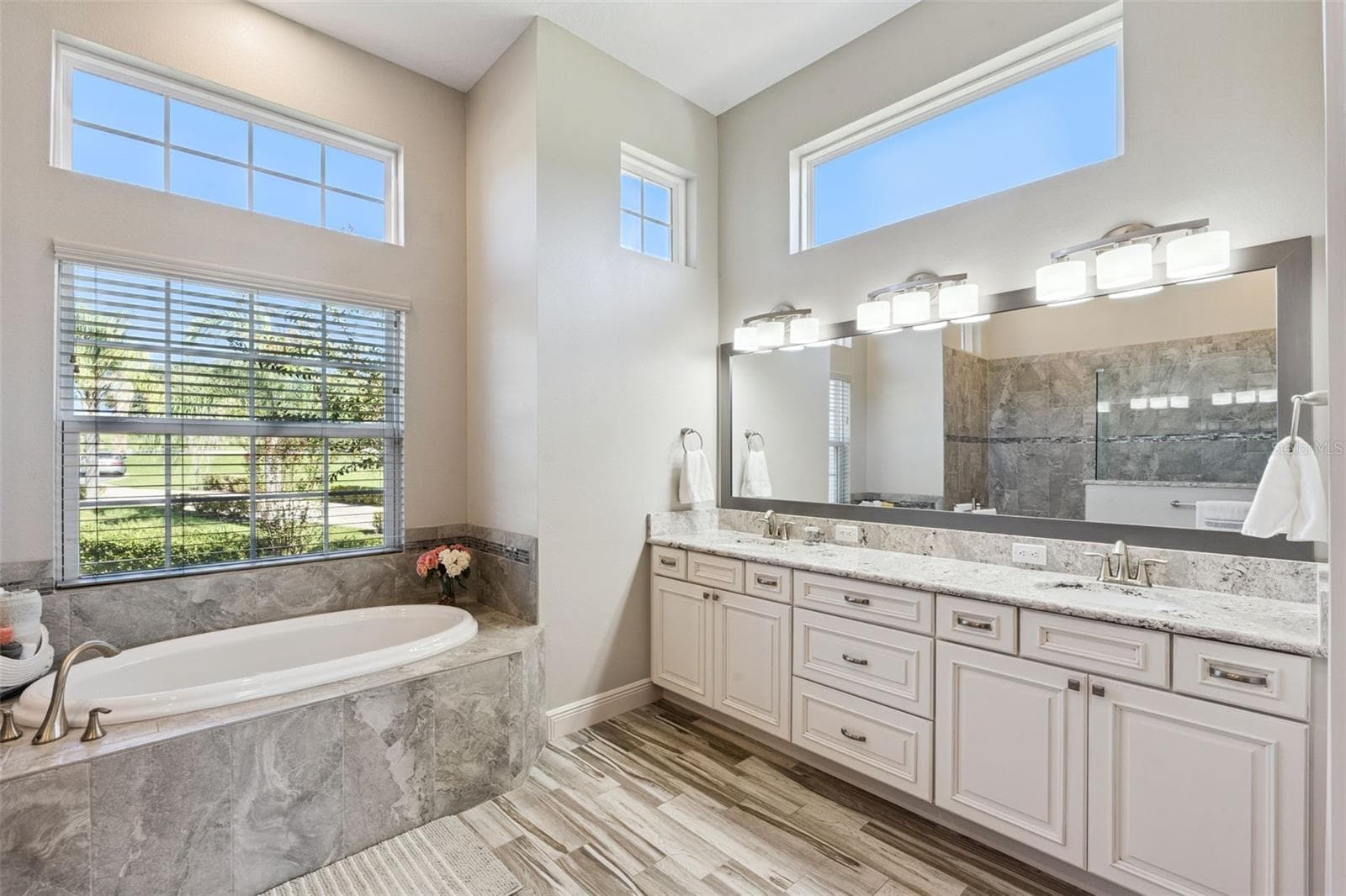 Light-filled primary en suite featuring elegant oversized windows, high-end lighting fixtures, and sleek quartz countertops. - 36819 WOLF CT, EUSTIS
