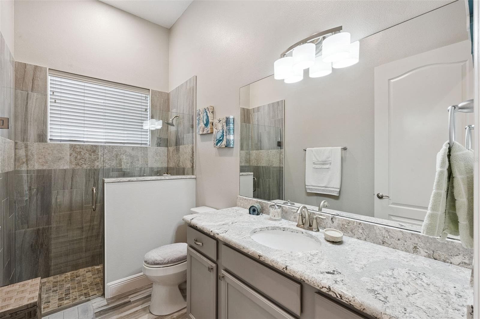 Bathroom 2, situated between bedrooms 2 and 3, features quartz countertops and a zero-entry walk-in shower. - 36819 WOLF CT, EUSTIS