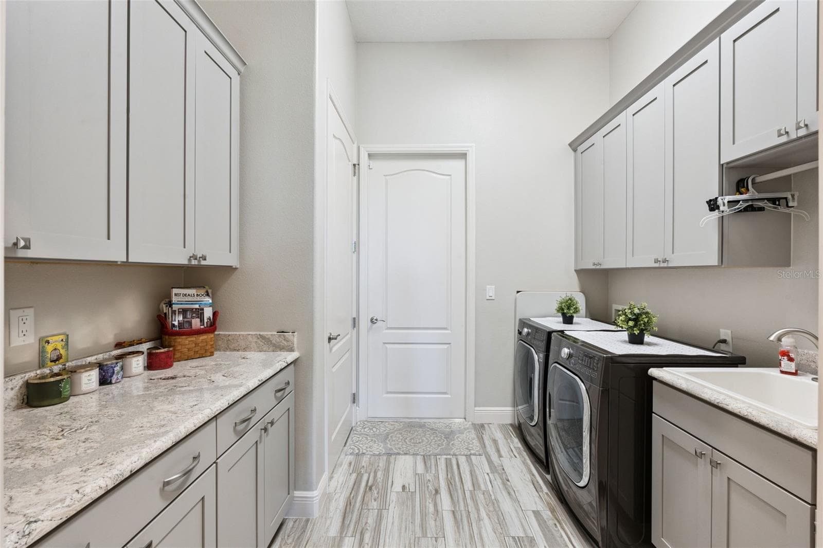Bright, functional laundry room featuring ample custom cabinetry, a dedicated folding station with a generous quartz countertop, and an undermount utility sink. - 36819 WOLF CT, EUSTIS
