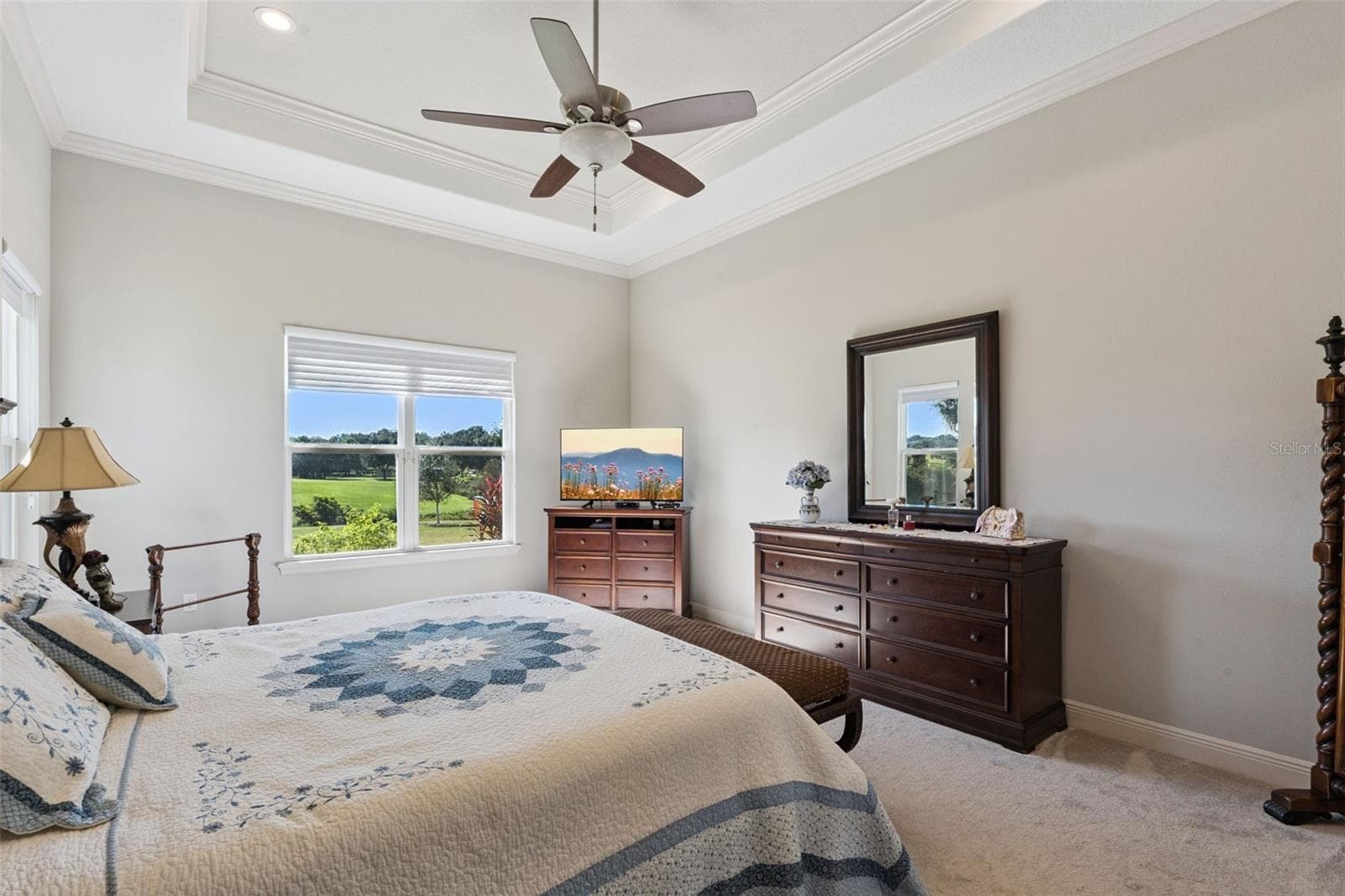 Spacious primary bedroom featuring a sophisticated trey ceiling, dual his-and-her closets, and a private en suite bathroom. - 36819 WOLF CT, EUSTIS