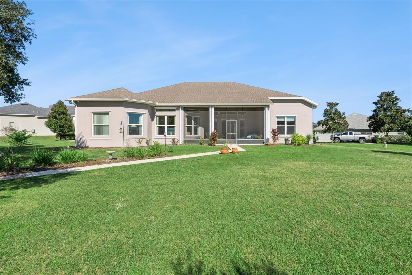 Rear exterior view featuring a paver walkway leading to the water. - 36819 WOLF CT, EUSTIS