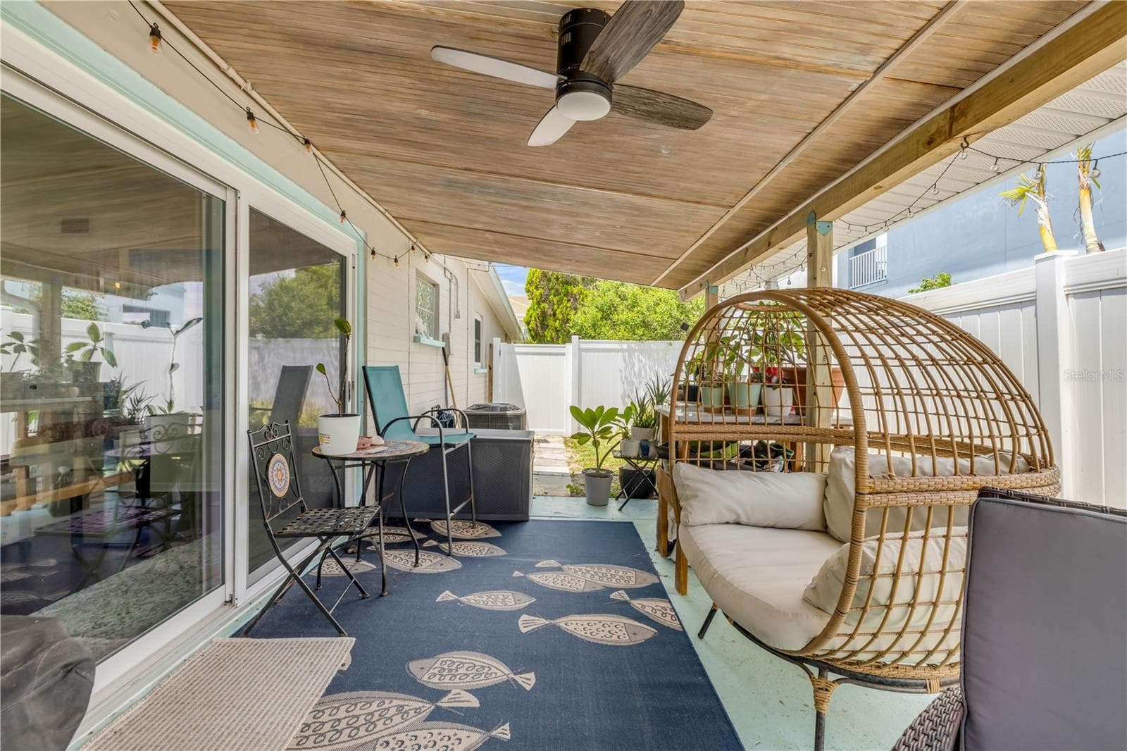 Covered patio with outdoor seating and a hanging chair. - 3929 S PENINSULA DR, PORT ORANGE