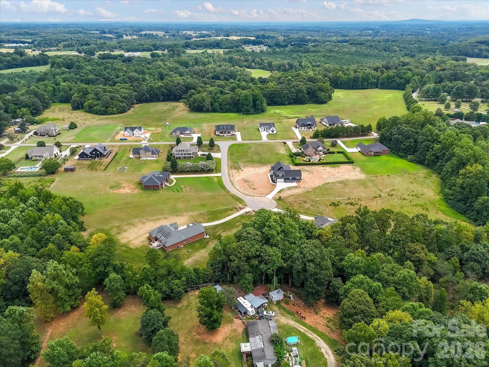 Expansive aerial view showcasing a peaceful cul-de-sac community with spacious homesites, beautiful custom homes, and lush wooded surroundings offering privacy and picturesque countryside scenery. - Lot 15 Peacehaven Place, Statesville