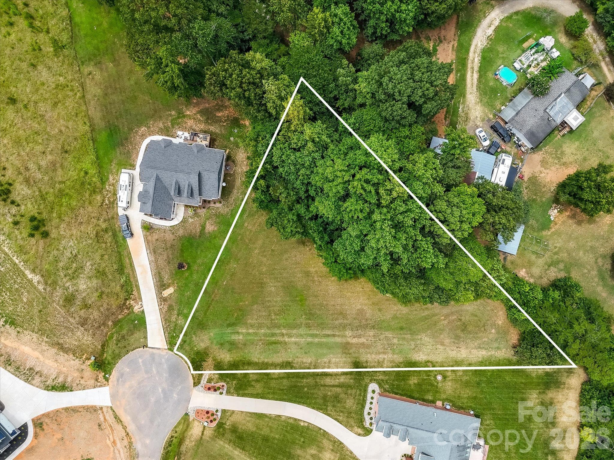 Overhead aerial view highlighting the spacious, triangular-shaped cul-de-sac homesite with clearly defined lot lines, expansive open green space, and a beautiful backdrop of mature trees offering privacy and natural beauty. - Lot 15 Peacehaven Place, Statesville