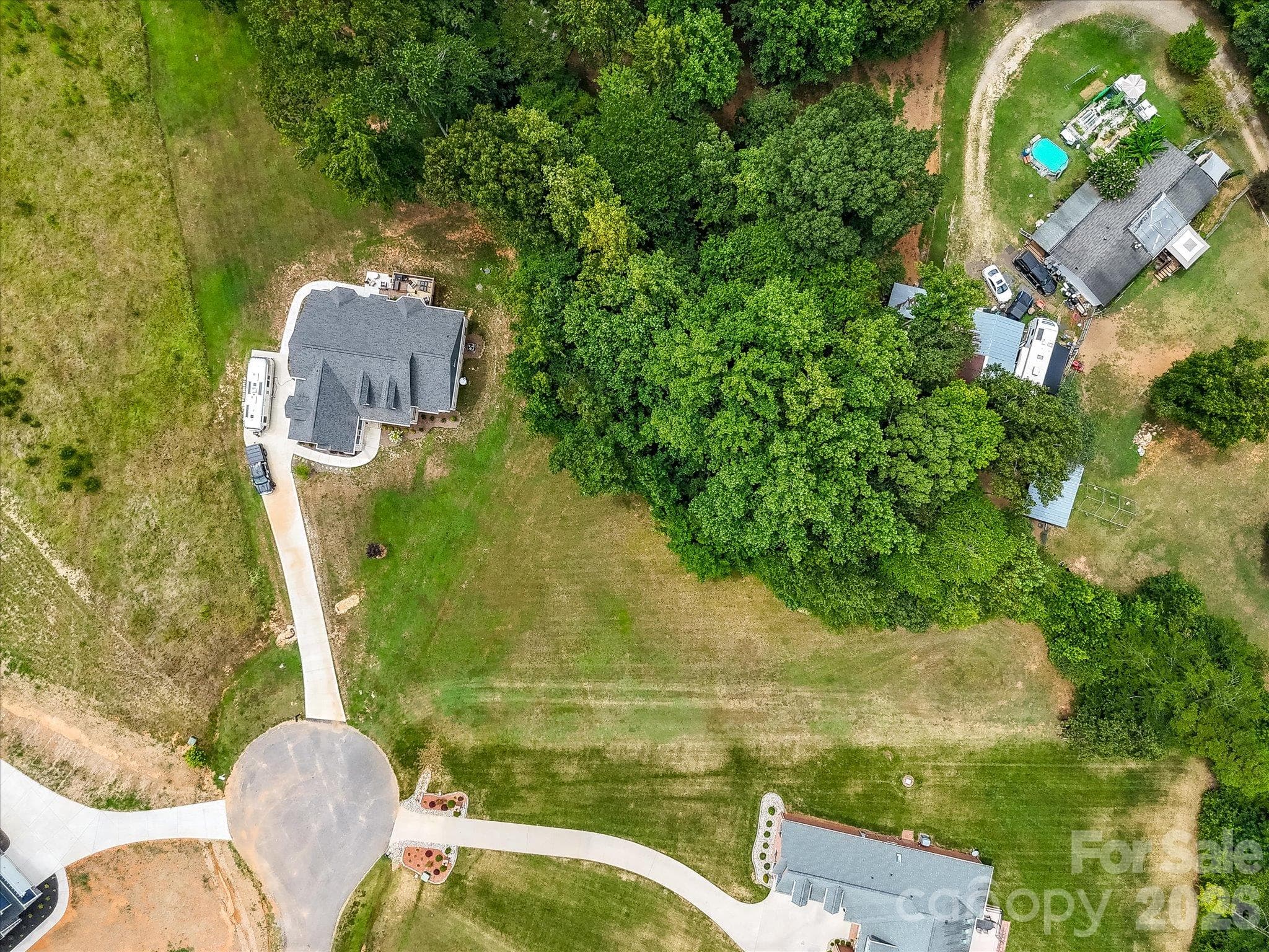 Overhead aerial view showcasing the spacious cul-de-sac homesite with an expansive open grassy area, mature trees, and a peaceful wooded backdrop offering privacy and a beautiful natural setting. - Lot 15 Peacehaven Place, Statesville
