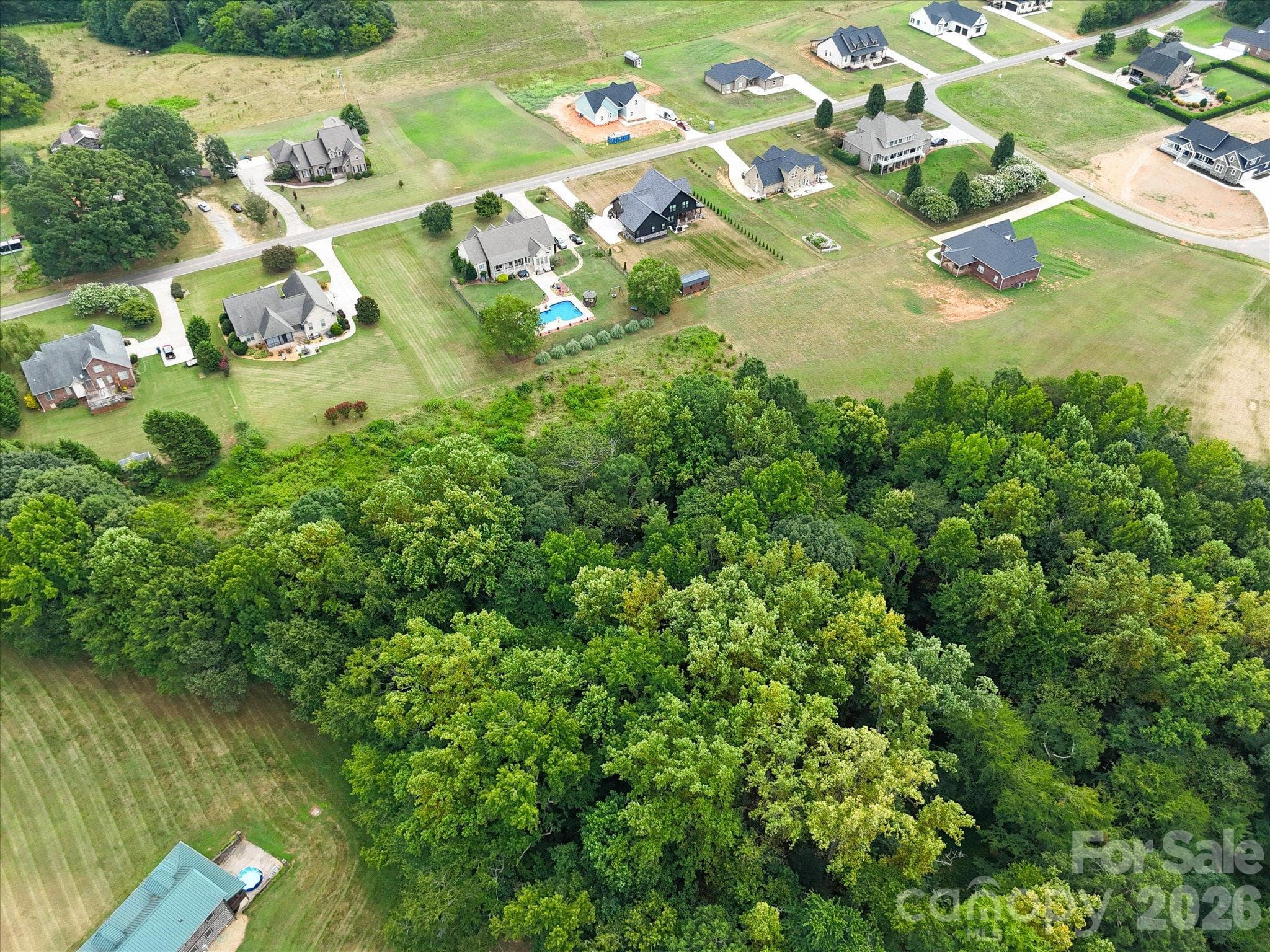 Aerial view showcasing the beautifully outlined homesite with a spacious, gently sloping landscape, a combination of open green space and mature trees, and a peaceful setting surrounded by attractive custom homes. - 494 New Salem Road, Statesville