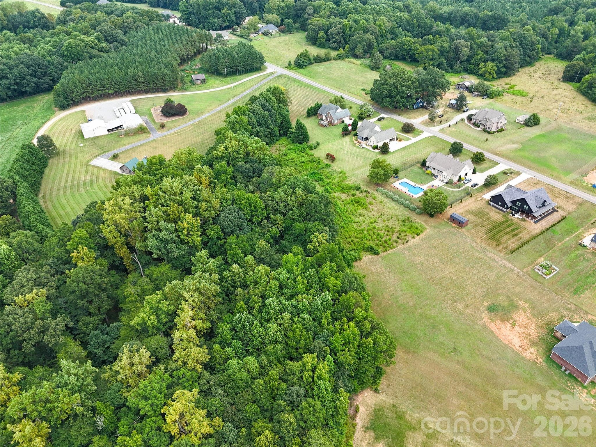 Expansive aerial view showcasing spacious homesites, beautiful custom residences, and peaceful countryside surroundings with lush green landscapes and mature woodlands providing a picturesque natural backdrop. - 494 New Salem Road, Statesville
