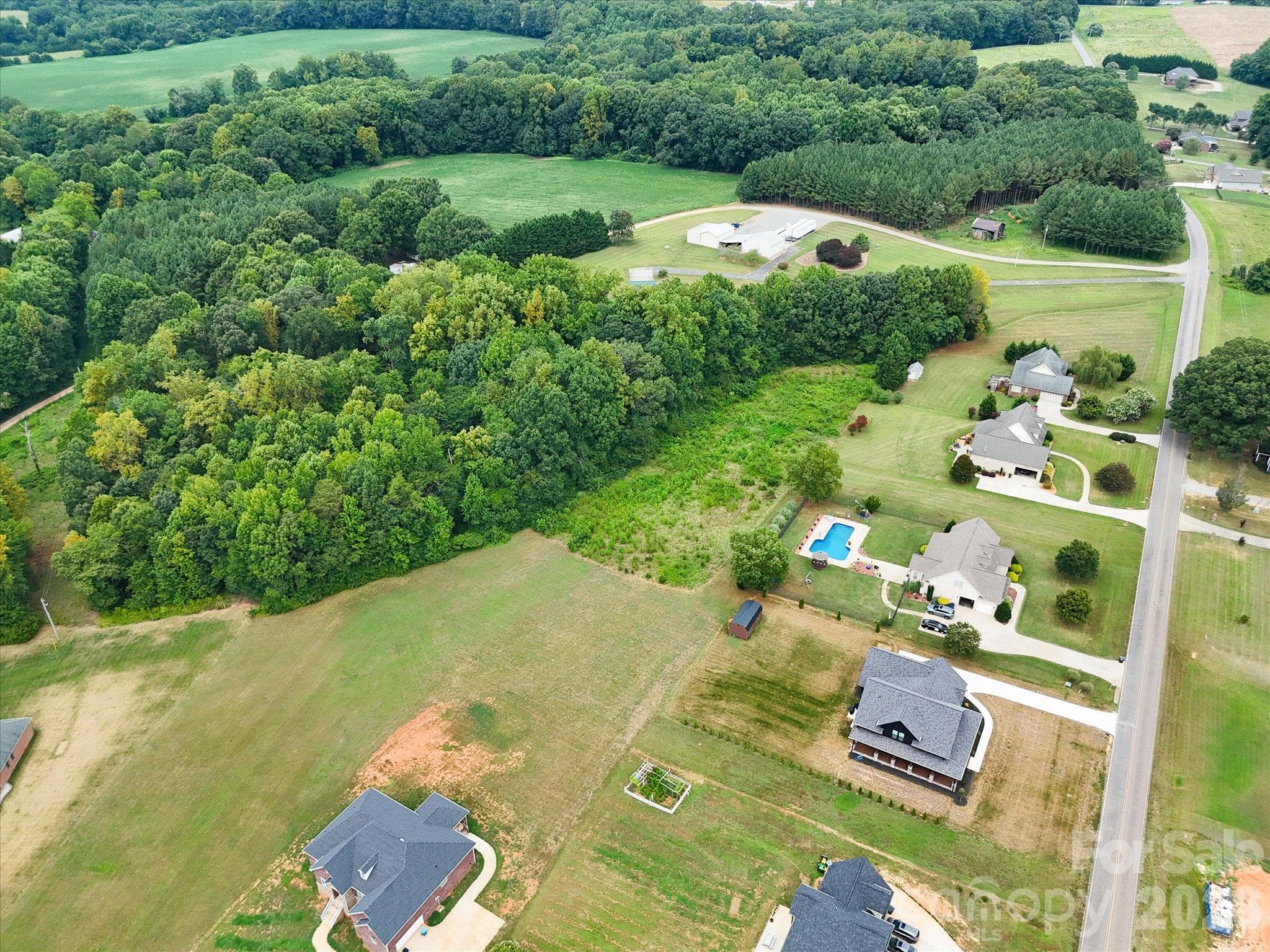Aerial view highlighting the outlined homesite with a spacious, partially wooded landscape, mature trees, and a peaceful residential setting surrounded by beautiful custom homes and expansive green spaces. - 494 New Salem Road, Statesville