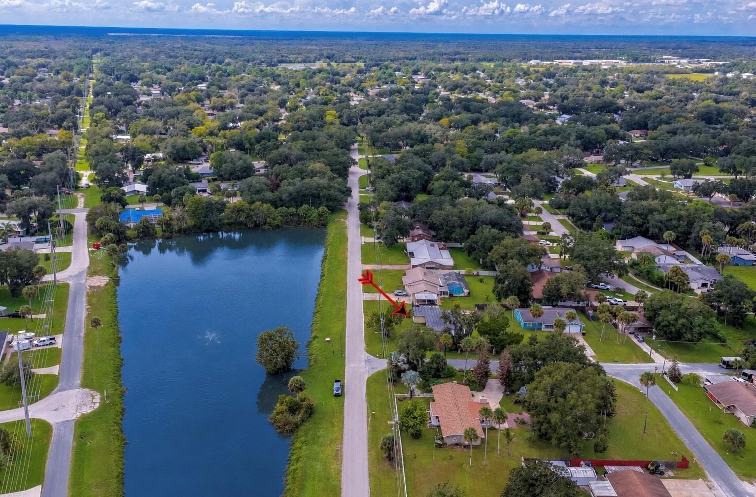 Wide-angle aerial perspective showing the home nestled in a quiet, tree-lined neighborhood adjacent to a large body of water. - 1101 16TH ST, EDGEWATER