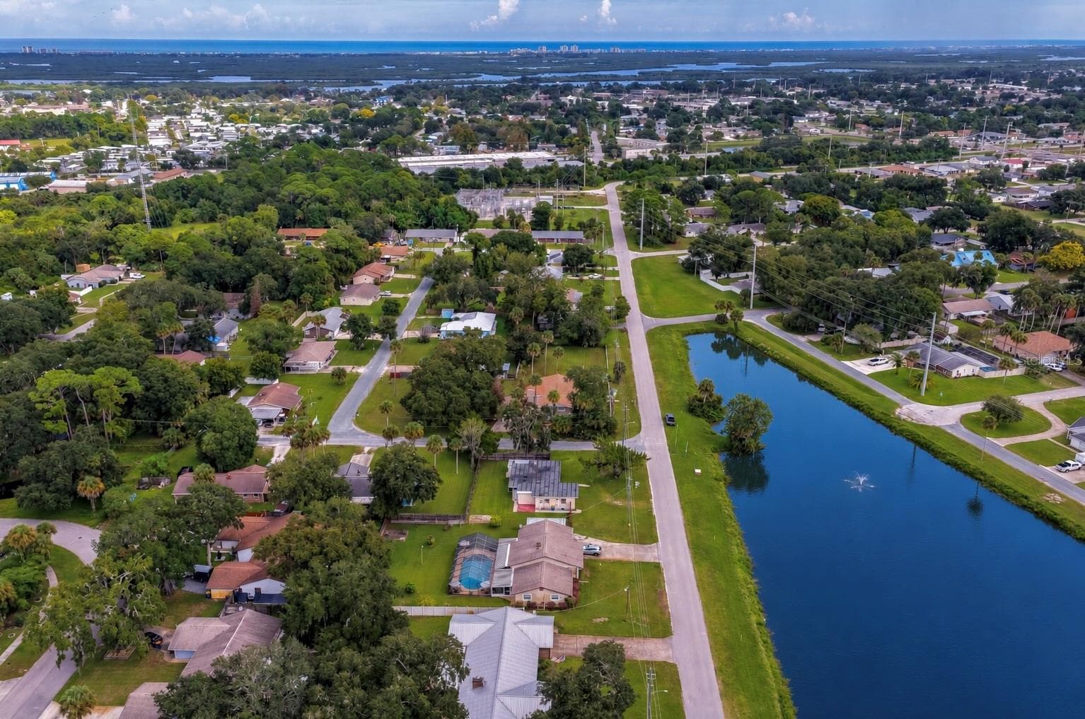 High-altitude aerial photograph highlighting the home's position near the neighborhood pond, surrounding woodland, and proximity to local community amenities. - 1101 16TH ST, EDGEWATER
