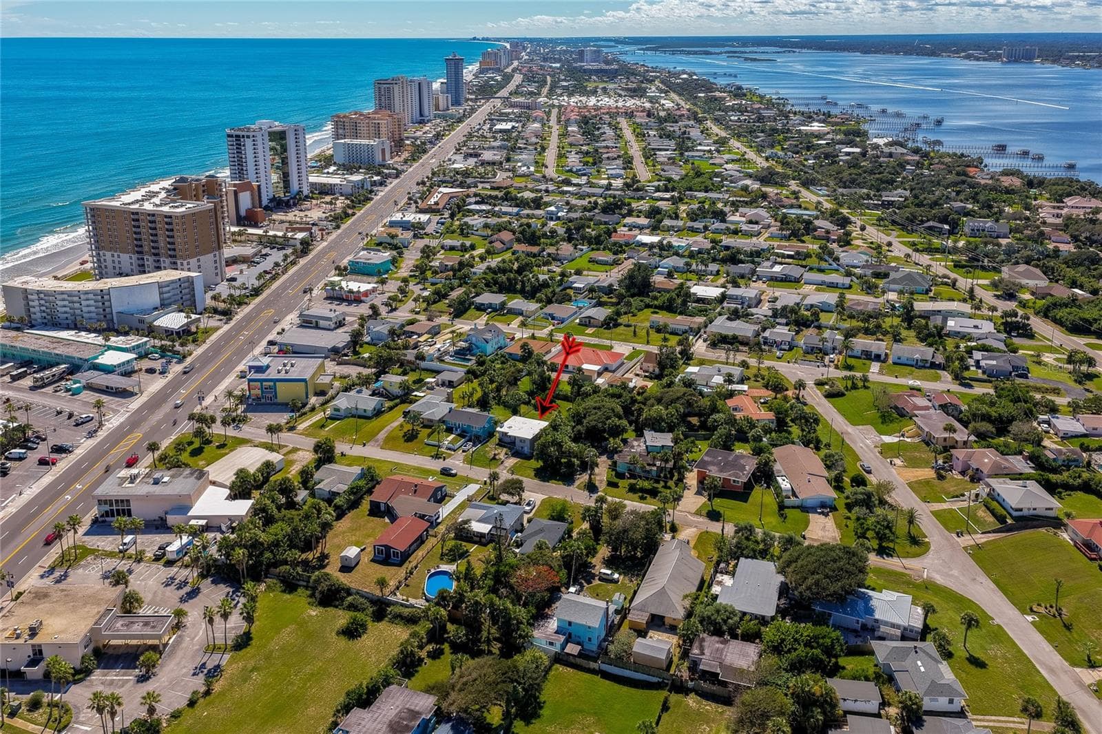 Panoramic aerial view capturing the property set between the ocean shoreline and the intracoastal waterway. The elevated perspective highlights the surrounding residential layout and scenic coastal landscape. - 128 MINERVA RD, DAYTONA BEACH