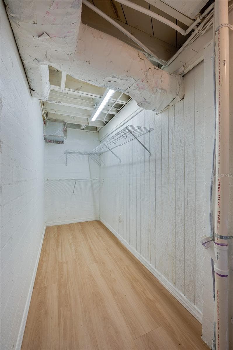 Long walk-in storage or closet space outfitted with upper wire shelving and light-colored LVP flooring. Exposed ceiling elements and overhead strip lighting maximize vertical utility. - 128 MINERVA RD, DAYTONA BEACH