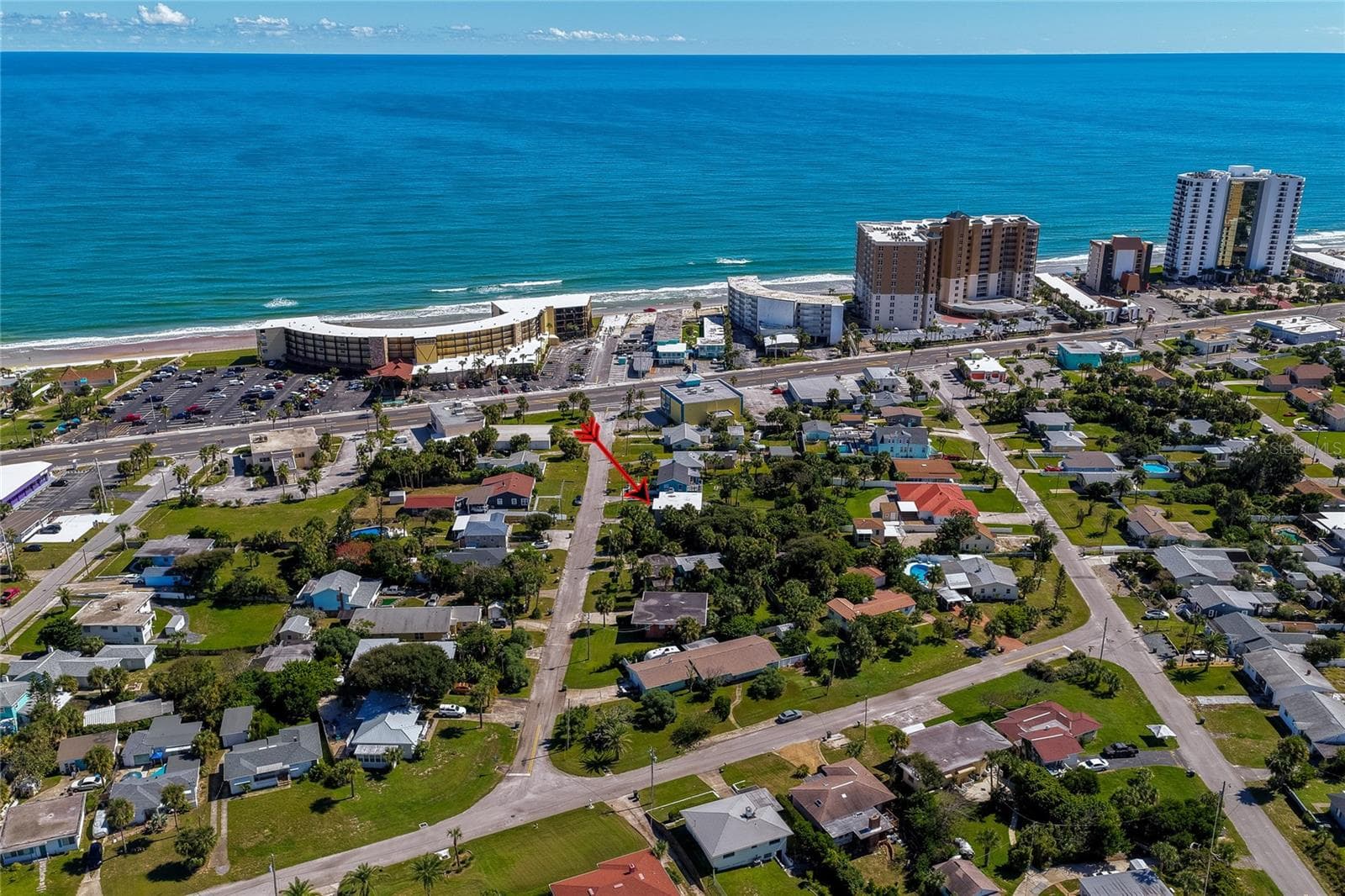 High-angle aerial shot highlighting the home's proximity to the Atlantic oceanfront and beach access corridors. Nearby high-rise resorts and coastal thoroughfares accentuate the prime location. - 128 MINERVA RD, DAYTONA BEACH