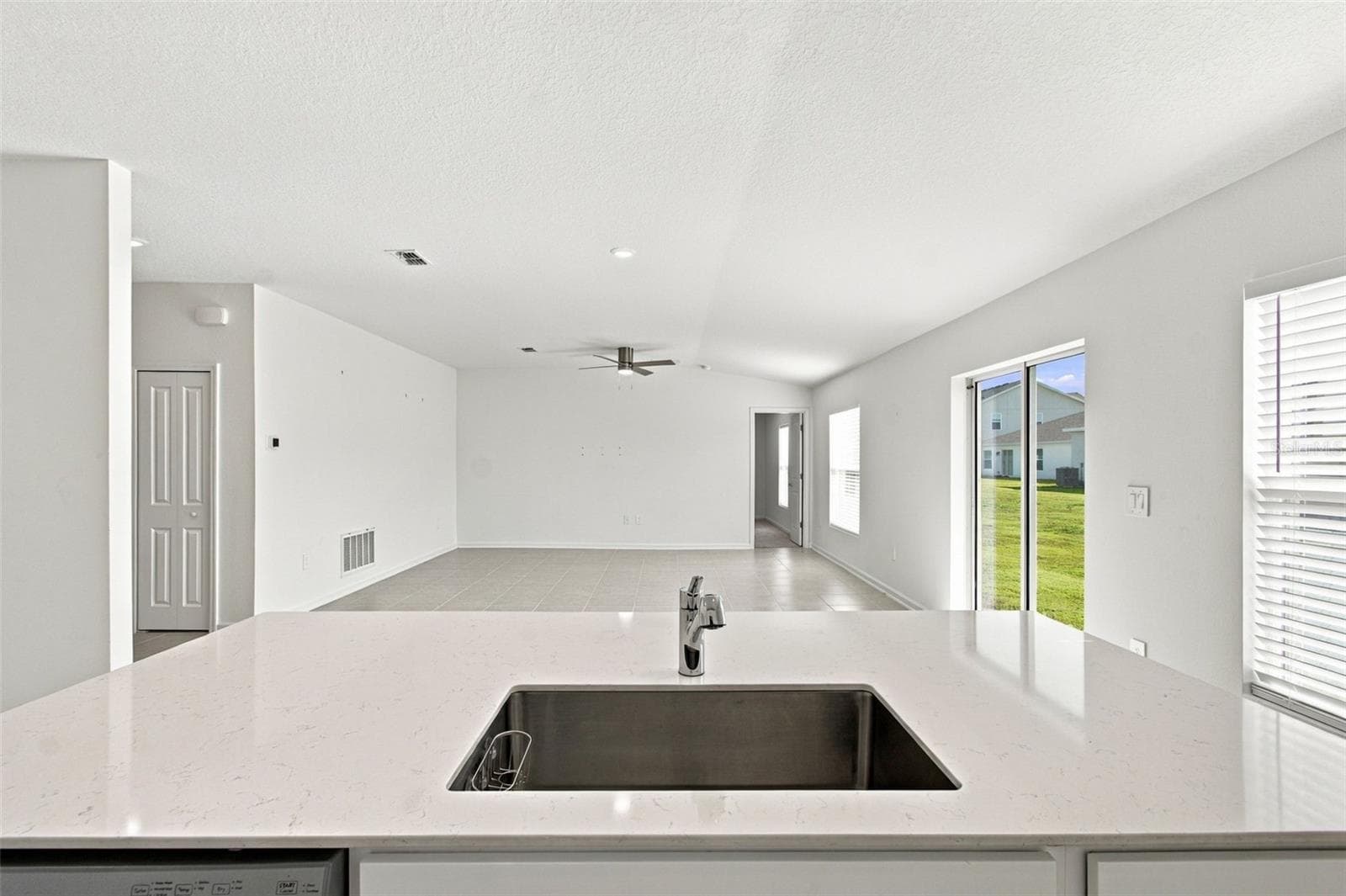 The kitchen offers a spacious island with breakfast bar, white Shaker-style cabinetry, and quartz countertops, all overlooking the dining and living areas. - 2007 FORAGE DR, KISSIMMEE