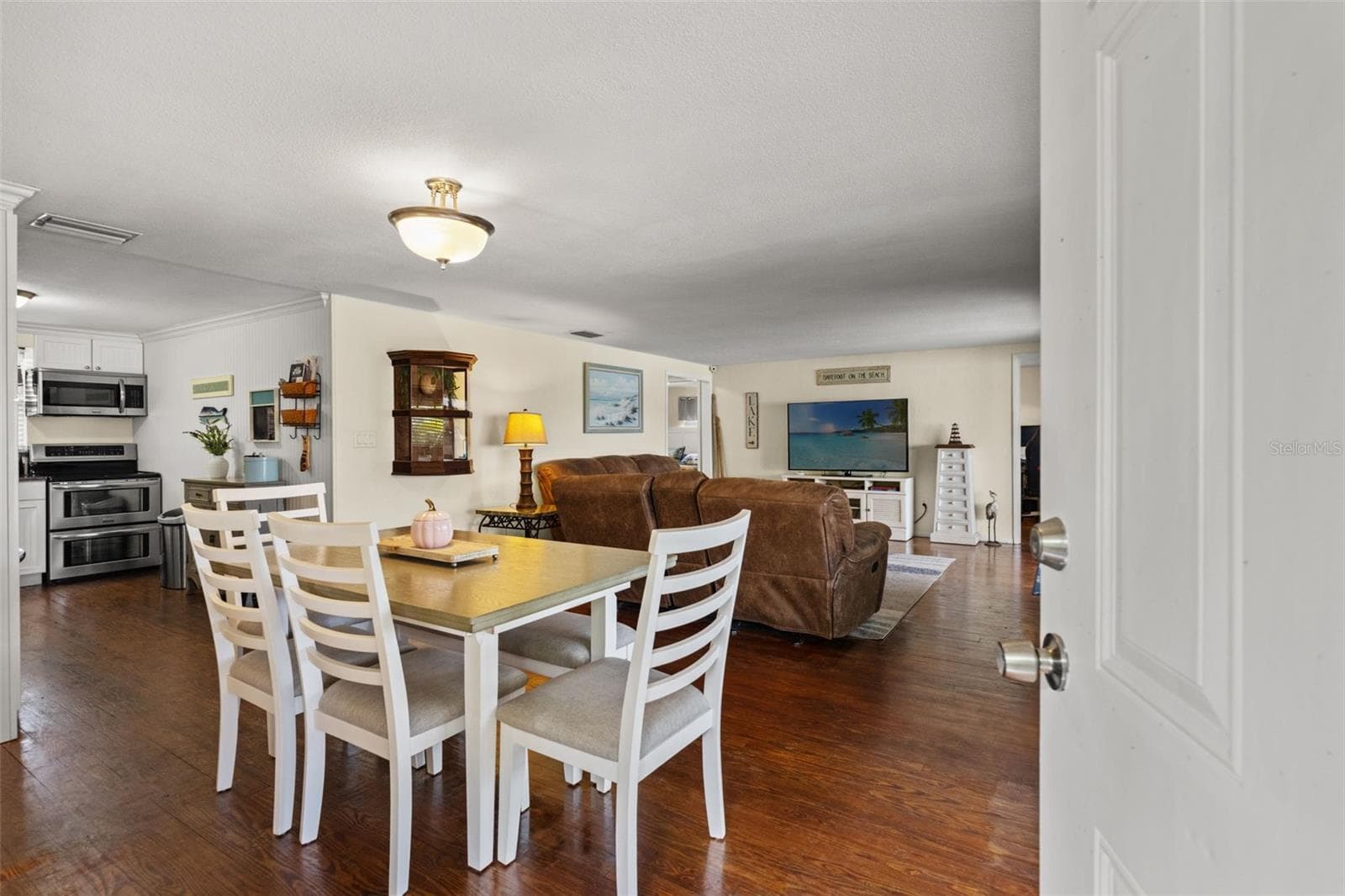 Welcome inside! Warm wood flooring extends throughout the open living and dining areas, creating an inviting space that flows naturally into the kitchen. The layout offers flexibility for everyday living and entertaining. - 13 FRESHWATER, PALM HARBOR