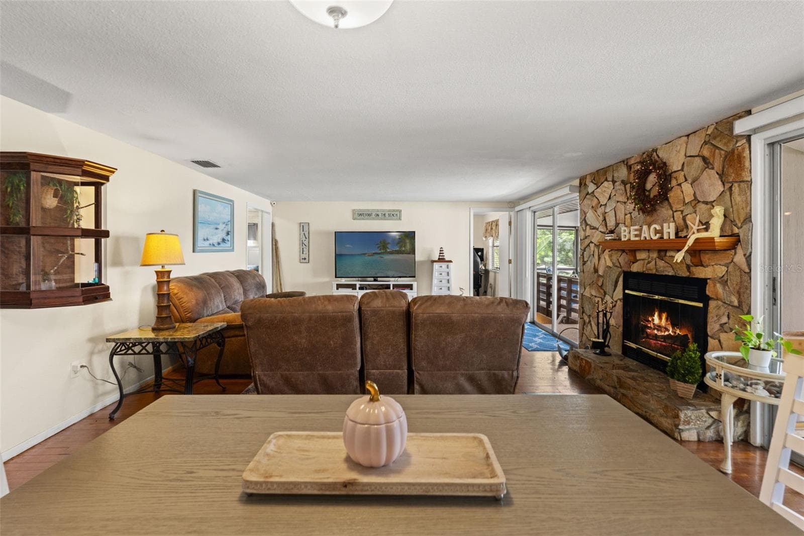 A beautiful stone fireplace brings warmth and character to the living room! The generous seating area features wood flooring and sliding glass doors leading toward the covered outdoor space. - 13 FRESHWATER, PALM HARBOR