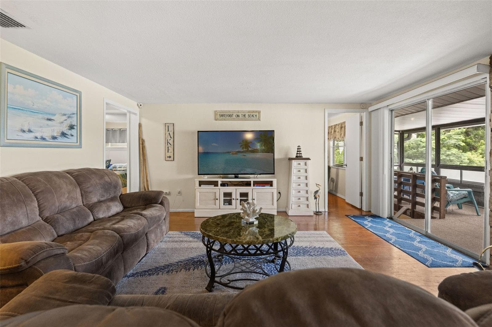 Indoor and outdoor living come together beautifully. The living room's sliding glass doors open to a spacious screened porch, while the stone fireplace adds warmth and character. It's a comfortable gathering space in every season. - 13 FRESHWATER, PALM HARBOR