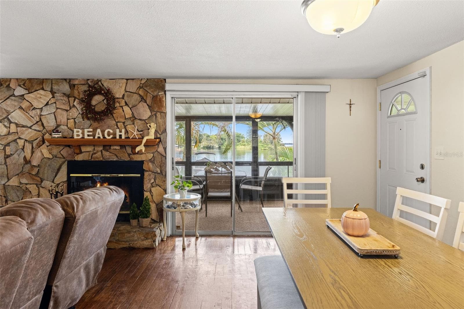 Imagine enjoying dinner with the water just beyond your windows! The dining area sits beside a striking stone fireplace, with sliding glass doors opening to a screened porch overlooking Lake Tarpon. - 13 FRESHWATER, PALM HARBOR