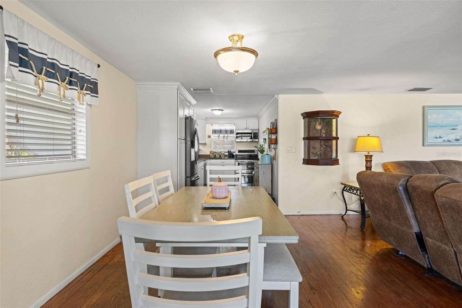 The dining area sits conveniently between the kitchen and living room, making meals and gatherings easy. Wood flooring, soft neutral walls, and natural light create a comfortable, welcoming atmosphere. - 13 FRESHWATER, PALM HARBOR