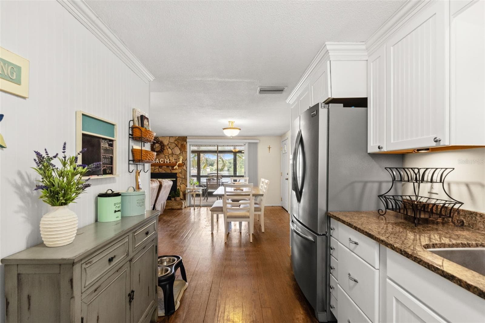 The kitchen opens directly to the dining and living areas, creating an easy flow throughout the upper level. White cabinetry, warm wood flooring, and a stainless steel refrigerator complement the home's relaxed coastal character. - 13 FRESHWATER, PALM HARBOR