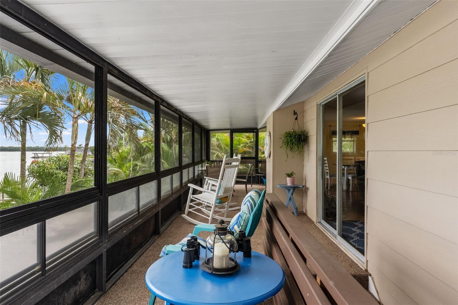 Imagine starting your mornings here! This long, screened porch overlooks the water and surrounding palms, with plenty of room for rocking chairs, conversation, and quiet relaxation. Sliding glass doors provide convenient access to the main living area. - 13 FRESHWATER, PALM HARBOR