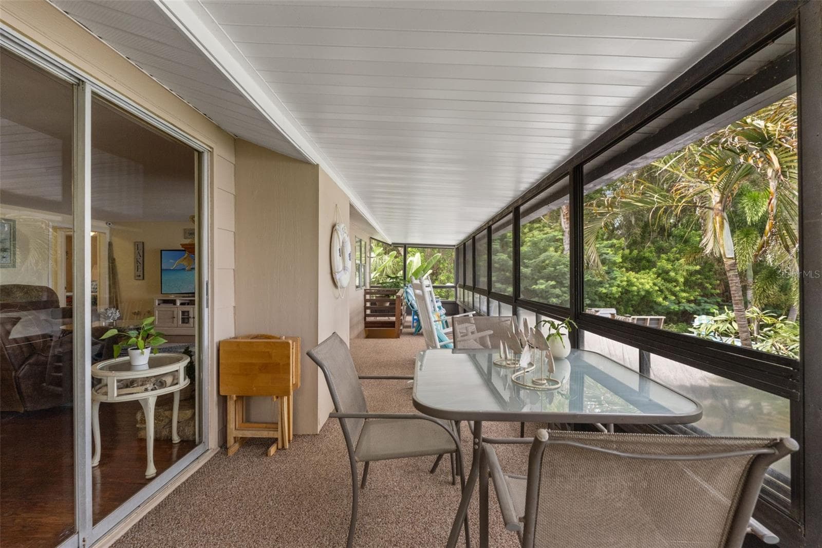 Outdoor dining with a tropical backdrop! This spacious screened porch offers room for a dining table and additional seating, making it an inviting extension of the upper-level living area. Sliding glass doors connect directly to the living room for easy entertaining. - 13 FRESHWATER, PALM HARBOR