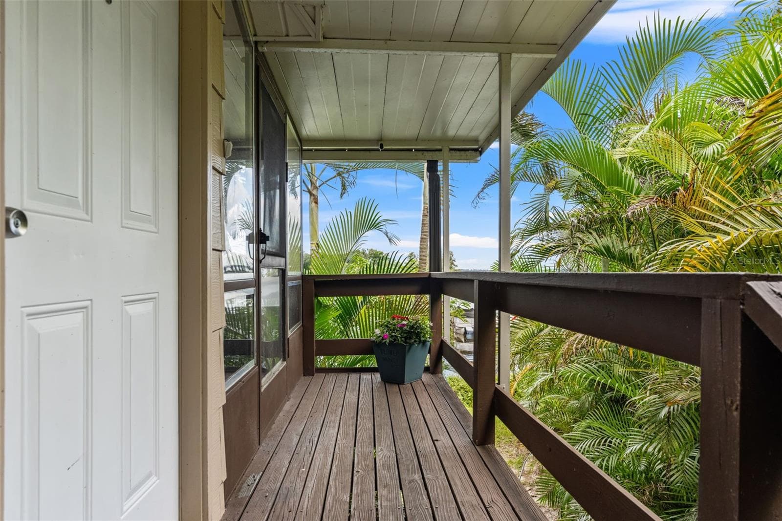 Surrounded by lush tropical palms, the covered upper-level entry offers a welcoming approach to the home, complete with wood decking, railings, and protection from the elements. - 13 FRESHWATER, PALM HARBOR