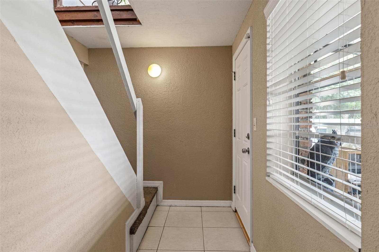 The lower level features its own exterior entrance, offering convenient access without passing through the upstairs living area. A tiled entryway, natural light, and interior stairway add to the functionality of this flexible layout. - 13 FRESHWATER, PALM HARBOR