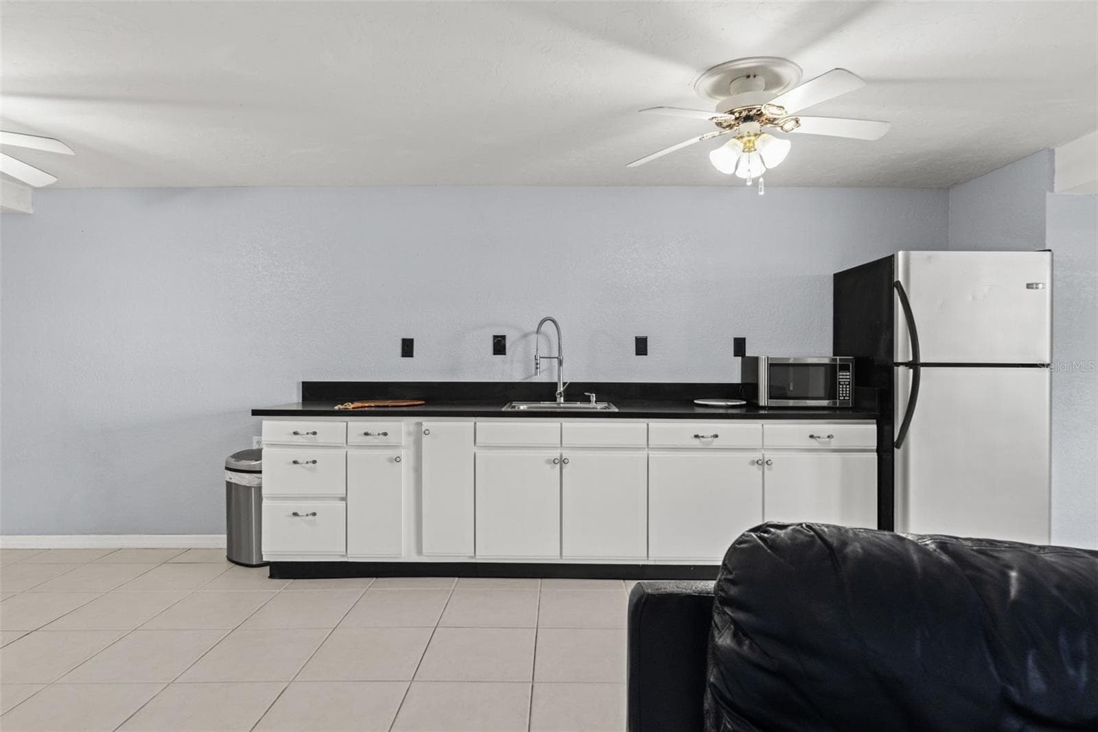 A closer look at the lower-level kitchenette reveals generous cabinet storage, dark countertops, a stainless-steel sink, refrigerator, and microwave. This additional food preparation area makes it easy to accommodate guests or enjoy snacks and refreshments without heading upstairs. - 13 FRESHWATER, PALM HARBOR