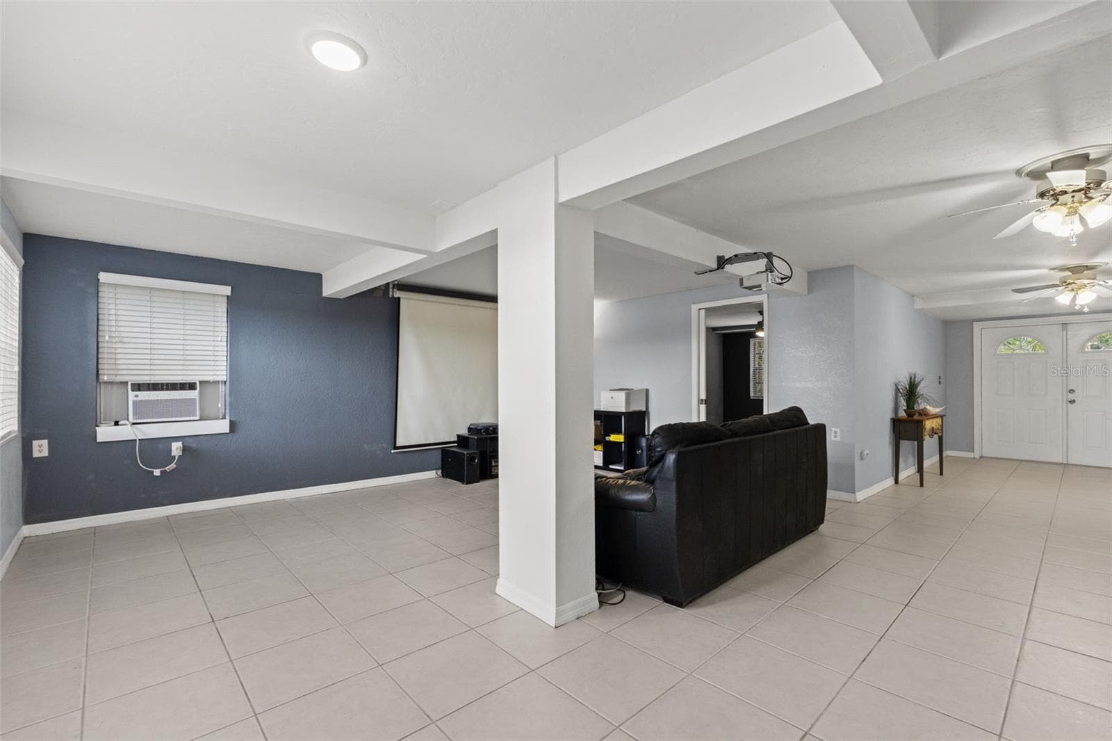 This wide-angle view highlights the versatility of the downstairs layout, with an open area adjoining the media room and easy access to the separate exterior entrance. Tile flooring runs throughout, providing a practical foundation for entertaining, recreation, or additional living space. - 13 FRESHWATER, PALM HARBOR