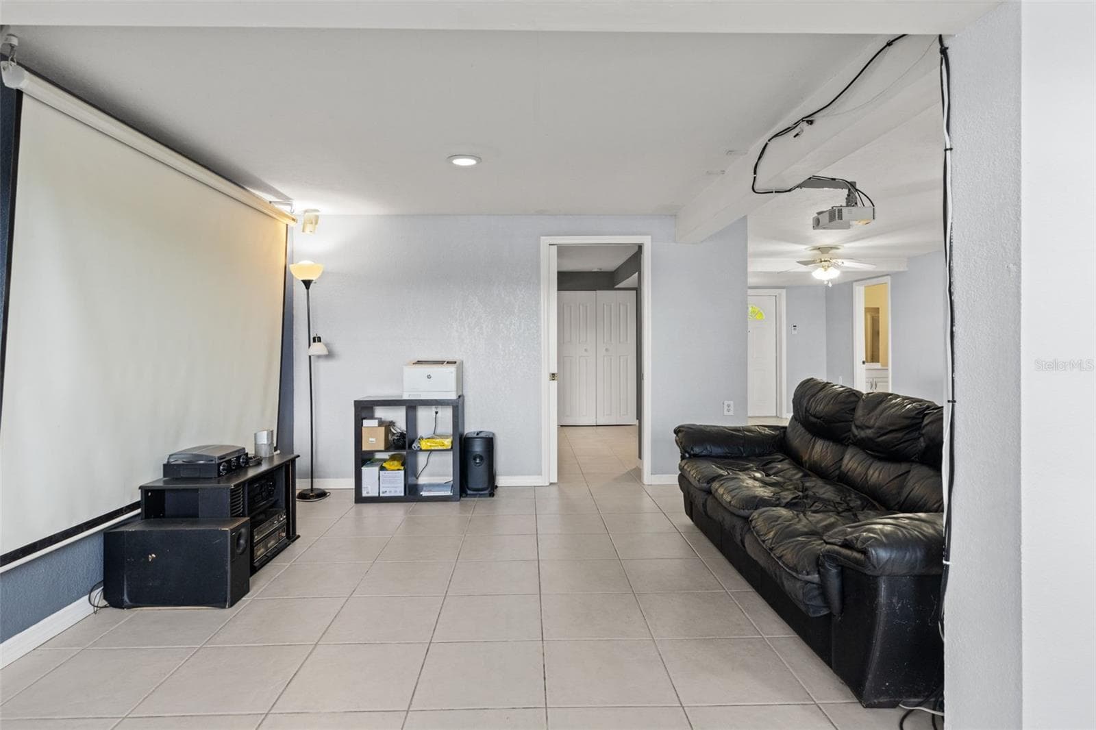 Bring the movie theater experience home with this lower-level entertainment space featuring a large projection screen and ceiling-mounted projector. The room offers space for comfortable seating and entertainment equipment, creating an inviting setting for movies, sports, and gatherings. - 13 FRESHWATER, PALM HARBOR