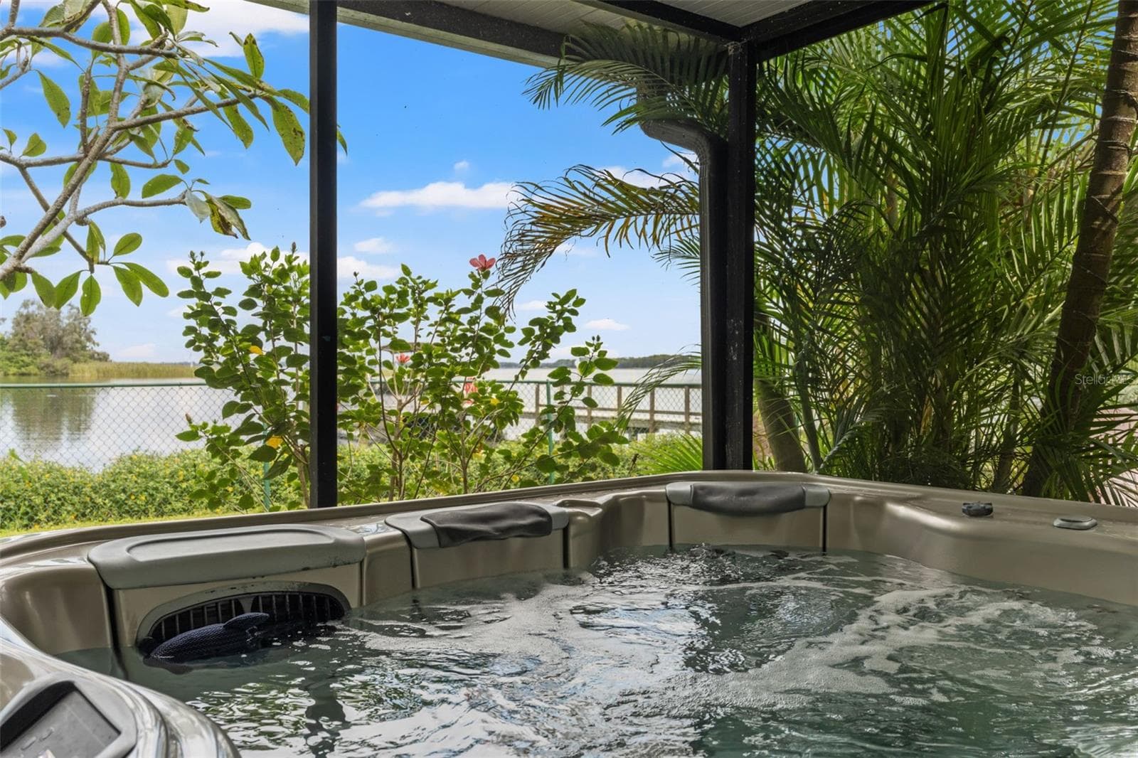 Imagine soaking in the bubbling hot tub while looking out toward the water! Tropical palms and flowering landscaping create a lush backdrop, while the screened enclosure makes this an inviting place to enjoy the outdoors. - 13 FRESHWATER, PALM HARBOR
