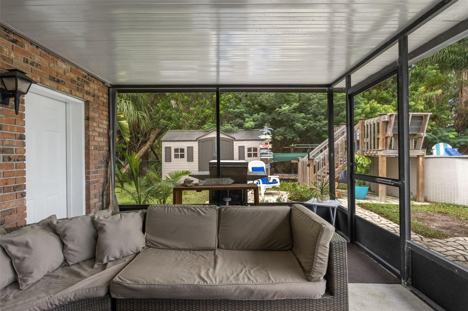 This covered, screened patio provides another comfortable outdoor gathering area, complete with sectional seating and access to the backyard. Beyond the enclosure, discover an above-ground pool, outdoor grilling area, and storage shed surrounded by mature trees. - 13 FRESHWATER, PALM HARBOR