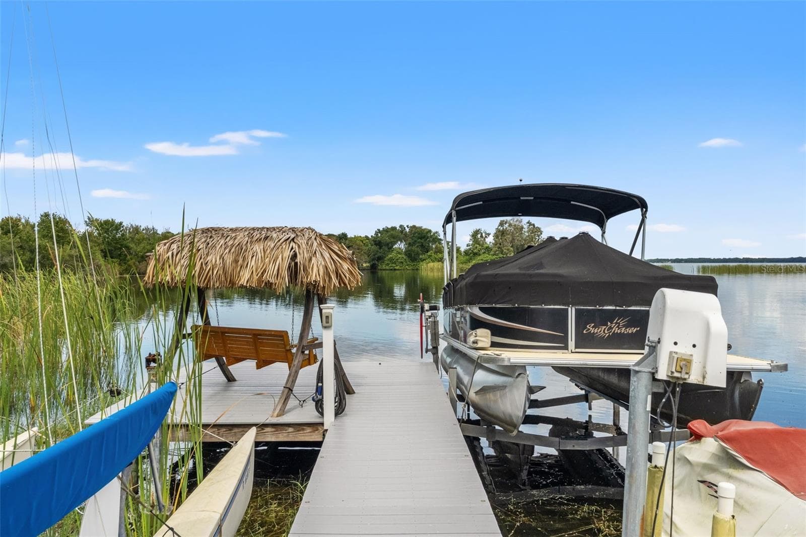 The waterfront dock offers more than just a place for your boat. A charming thatched-roof swing creates a shaded retreat beside the pontoon boat lift, perfect for enjoying a morning coffee, watching wildlife, or relaxing after a day on the water. - 13 FRESHWATER, PALM HARBOR