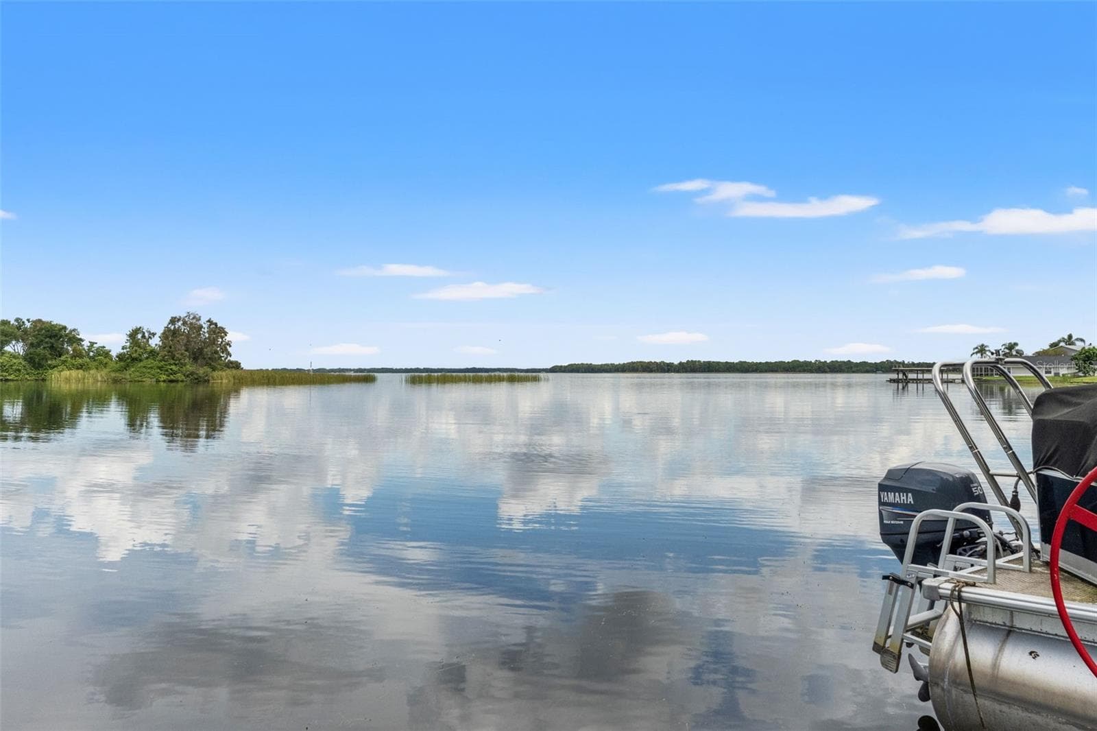 This is what lakefront living is all about! Sweeping views extend across the calm water toward a distant tree-lined shoreline. Whether you're enjoying an early morning sunrise, watching passing wildlife, or heading out for an afternoon on the boat, the waterfront setting is the star. - 13 FRESHWATER, PALM HARBOR