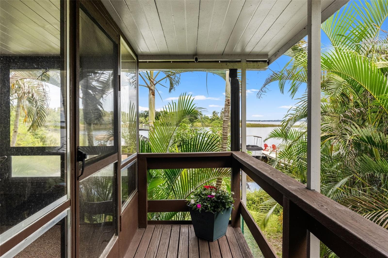Your first glimpse of the waterfront! From the covered upper-level entry, enjoy views through the palms toward the water and private dock—a beautiful introduction to the Florida lifestyle waiting here. - 13 FRESHWATER, PALM HARBOR