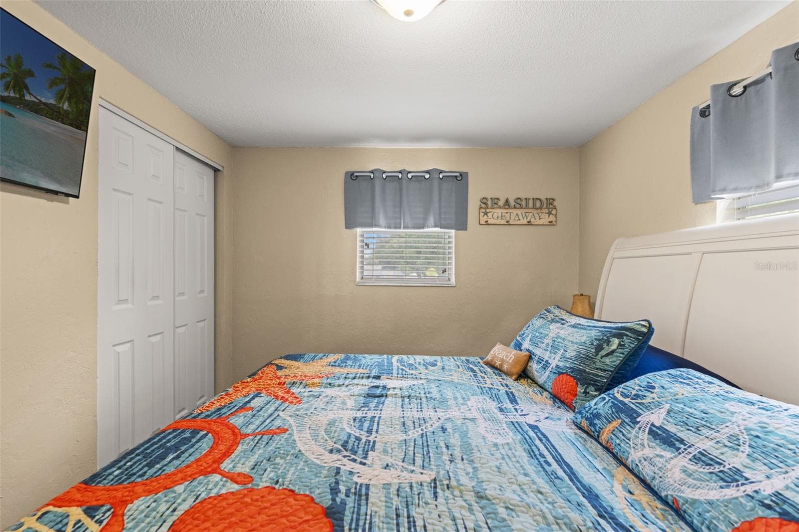 Another view of this inviting bedroom highlights the double-door closet, wood flooring, and natural light from two windows. A comfortable space for family or overnight guests. - 13 FRESHWATER, PALM HARBOR