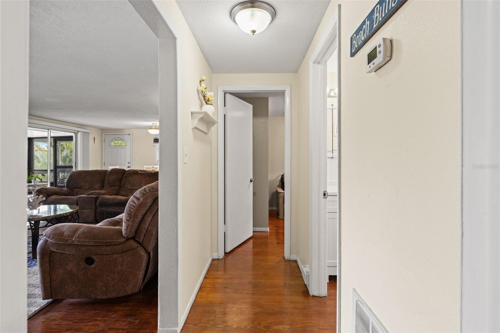 Wood flooring continues through the hallway, connecting the bedrooms and bathroom to the main living area. The convenient layout keeps everything within easy reach on the upper level. - 13 FRESHWATER, PALM HARBOR