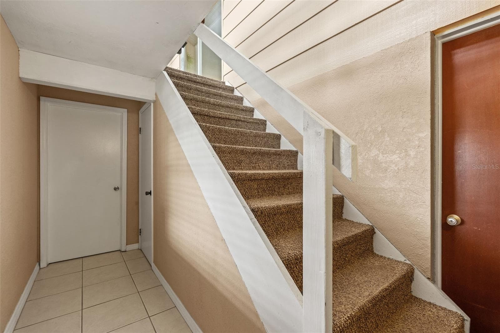 The interior stairway provides convenient access between the upper and lower levels. Neutral finishes, tile flooring, and nearby doorways connect the home's different living spaces. - 13 FRESHWATER, PALM HARBOR