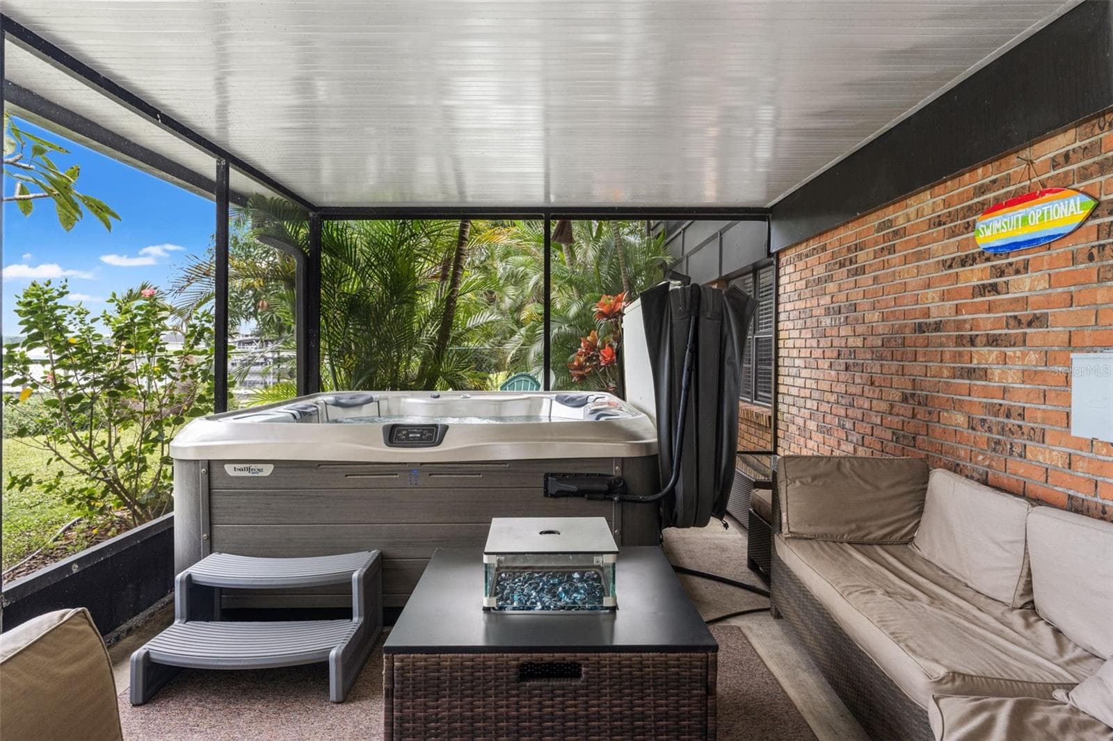 Relax in the hot tub while enjoying the privacy of the screened enclosure and surrounding tropical greenery. With comfortable seating nearby, this covered outdoor space offers a wonderful setting for year-round Florida relaxation. - 13 FRESHWATER, PALM HARBOR