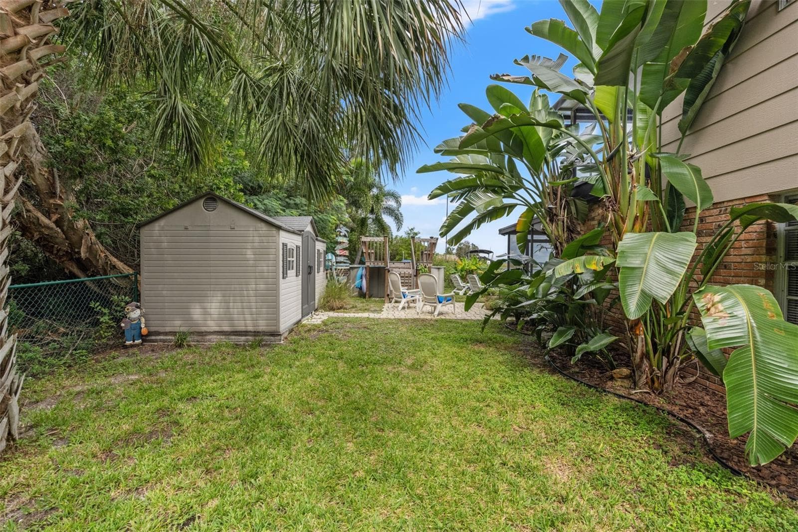 Tropical landscaping surrounds this spacious side yard, complete with a freestanding storage shed for outdoor equipment, tools, and recreational gear. The grassy area connects to the backyard's patio, pool, and waterfront amenities. - 13 FRESHWATER, PALM HARBOR
