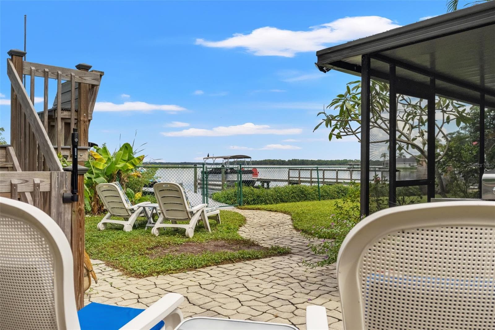 From your backyard patio, enjoy beautiful views across the water. A winding paver pathway leads past lounge chairs toward the fenced waterfront and dock, making it easy to move between relaxing in the yard and spending time on the water. - 13 FRESHWATER, PALM HARBOR