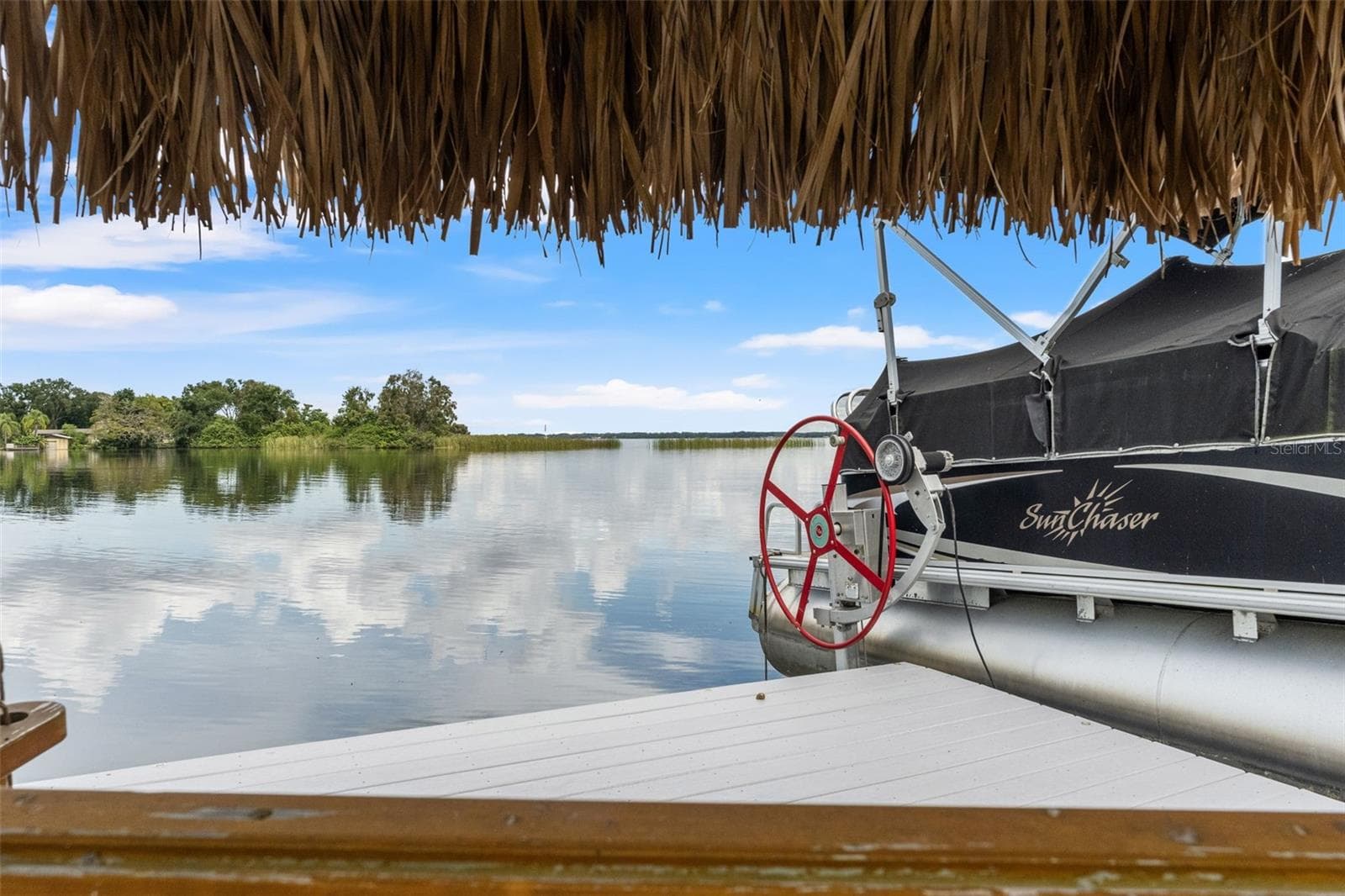Imagine relaxing beneath the thatched roof, enjoying a gentle breeze and uninterrupted views across the lake. This dockside seating area provides a peaceful escape just steps from your boat, bringing a little vacation atmosphere to everyday life. - 13 FRESHWATER, PALM HARBOR