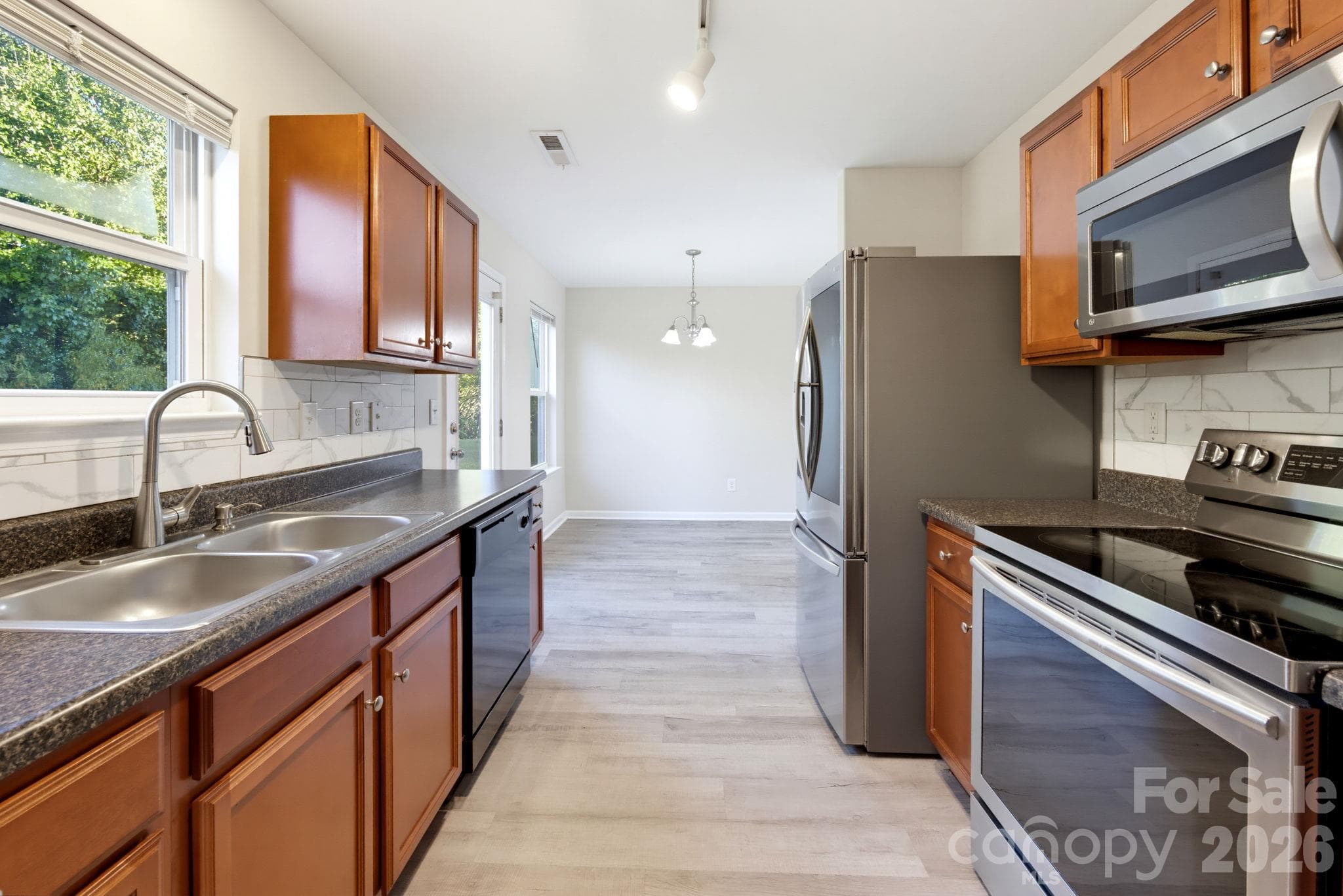 Kitchen featuring warm wood cabinetry, ample counter space, and stainless steel appliances. - 5718 Natick Drive, Charlotte